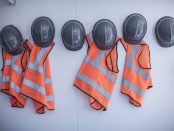 Rows of hard hats and high vis jackets on portable cabin wall Source: imagesourcecurated